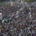 
              Supporters of Pakistan's main opposition 'Tehreek-e-Insaf party' listen to  Imran Khan at a rally in Lahore, Pakistan, Friday, Oct. 28 2022. Khan along with thousands of his supporters in a large convoy of buses and cars Friday began his much-awaited march on the capital Islamabad from the eastern city of Lahore on Friday to demand the holding of snap elections, a sign of deepening political turmoil. (AP Photo/K.M. Chaudary)
            