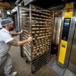 
              FILE- An employee pushes bread rolls into one of the gas heated ovens in the producing facility in Cafe Ernst in Neu Isenburg, Germany, Monday, Sept. 19, 2022. Andreas Schmitt, head of the local bakers' guild, said some small bakeries are contemplating giving up due to the energy crisis. (AP Photo/Michael Probst, File)
            
