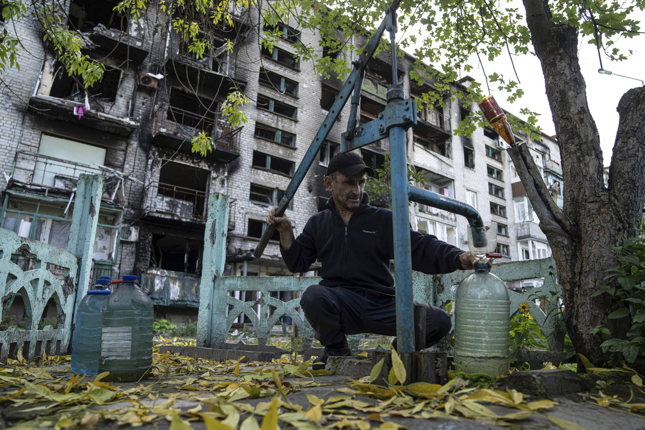 A man pumps water in front of destroyed house in the recently recaptured town of Lyman, Ukraine, Mo...