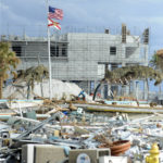 
              Flags fly over the rubble of Fort Myers Beach, Fla., on Sunday, Oct. 9, 2022. Located on a coastal barrier island, the resort town was badly damaged by Hurricane Ian. (AP Photo/Jay Reeves)
            