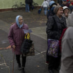 
              People queue to receive a daily ration of bread in a school in Mykolaiv, Tuesday, Oct. 25, 2022. Mykolaiv residents pick up bread from the only food distribution point in Varvarivka, a Mykolaiv district where thousands of people live. One person is allowed to receive free bread just once in three days. (AP Photo/Emilio Morenatti)
            