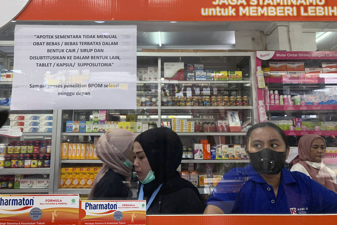 Employees wait for customers at a counter displaying a notification saying that the sale of medicin...