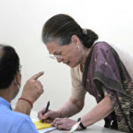 
              India's main opposition Congress party's interim president Sonia Gandhi signs to receive ballot paper to cast her vote for the party president elections, in New Delhi, India, Monday, Oct.17, 2022. Nearly 9,000 party delegates are voting on Monday to elect a new president with members of its dominant Nehru-Gandhi dynasty staying out of the race after a gap of 24 years. Vote-counting and results are scheduled for Wednesday. (AP Photo/Manish Swarup)
            
