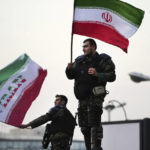 
              Two anti-riot police officers wave the Iranian flags during a street celebration after Iran defeated Wales in Qatar's World Cup, at Sadeghieh Sq. in Tehran, Iran, Friday, Nov. 25, 2022. Iran's political turmoil has cast a shadow over Iran's matches at the World Cup, spurring tension between those who back the team and those who accuse players of not doing enough to support the protests that started Sept. 16 over the death of a 22-year-old woman in the custody of the morality police. (AP Photo/Vahid Salemi)
            