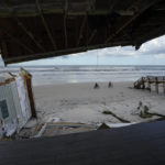 
              People bike past the wreckage of a home, half of which was toppled when the beach below and in front of it was eroded, following the passage of Hurricane Nicole, Friday, Nov. 11, 2022, in Wilbur-By-The-Sea, Fla. Homeowner Meister said he had applied for a permit to build a permanent seawall after the passage of Hurricane Ian in late September, but it had not yet been granted.(AP Photo/Rebecca Blackwell)
            