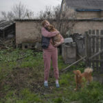 
              Iryna Stetcenko pets a dog in a yard of her house in the village of Demydiv, about 40 kilometers (24 miles) north of Kyiv, Ukraine, Tuesday, Nov. 2, 2022. Environmental damage caused by Ukraine’s war is mounting in the 8-month-old conflict, and experts warn of long-term health consequences for the population.  The World Wildlife Fund in Ukraine says more than 6 million people have limited or no access to clean water. “We don’t have another option. We don’t have money to buy bottles,” Iryna Stetcenko told The Associated Press. (AP Photo/Andrew Kravchenko)
            