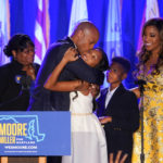 
              Democrat Wes Moore, second from left, hugs his daughter, Mia, center, as Moore's mother, Joy Thomas Moore, left, his son, Jamie, second from right, and his wife, Dawn, look on after he spoke to supporters during an election night gathering after he was declared the winner of the Maryland gubernatorial race, Tuesday, Nov. 8, 2022, in Baltimore. (AP Photo/Julio Cortez)
            
