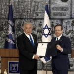 
              Israel's Likud Party leader Benjamin Netanyahu, left, and Israel's President Isaac Herzog pose on the podium after Herzog assigned Netanyahu the task of forming a government, in Jerusalem, Sunday, Nov. 13, 2022. Israel's president officially tapped Netanyahu to form a government on Sunday, ushering the long-serving leader back to power after a one-year hiatus. With Netanyahu comes what's expected to be Israel's most right-wing coalition ever. (AP Photo/ Maya Alleruzzo)
            