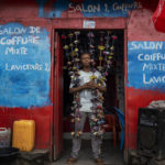 
              Fabrice, 20, poses in front of his hairdressing salon in Goma, Democratic Republic of Congo, Saturday Nov. 26, 2022.At a time of tension and economic uncertainty, the bold names and brightly colored storefronts bring a sense of normalcy to residents who have contended with conflict and natural disasters such as volcanic eruptions for decades. (AP Photo/Jerome Delay)
            
