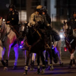 
              Law enforcement officers on horseback patrol the street outside the Maricopa County Recorders Office, Tuesday, Nov. 8, 2022, in Phoenix. (AP Photo/Matt York)
            