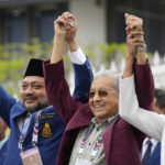 
              Malaysia's former Prime Minister Mahathir Mohamad, center, chairman of Gerakan Tanah Air (Homeland Movement) party, raises his hands with others candidates outside the nomination center after their nomination being accepted in Langkawi Island, Saturday, Nov. 5, 2022, Malaysia. Campaigning for Malaysia's general elections formally started Saturday, in a highly competitive race that will see Barisan Nasional, the world's longest-serving coalition seeking to regain its dominance four years after a shocking electoral loss.(AP Photo/Vincent Thian)
            