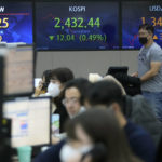 
              A currency trader passes by screens showing the Korea Composite Stock Price Index (KOSPI), center, and the exchange rate of South Korean won against the U.S. dollar, right, at the foreign exchange dealing room of the KEB Hana Bank headquarters in Seoul, South Korea, Monday, Nov. 21, 2022. Asian stock markets sank Monday after Wall Street ended with a loss for the week amid anxiety about Federal Reserve plans for more interest rate hikes to cool inflation. (AP Photo/Ahn Young-joon)
            