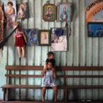 
              Daughters of fishermen, Tatiana and Andresa, top, sit at their home in San Raimundo settlement in Carauari, Amazonia State, Brazil, Monday, Sept. 5, 2022. Thirty-four families call the area home. (AP Photo/Jorge Saenz)
            