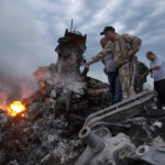 
              FILE - People inspect the crash site of a passenger plane near the village of Grabovo, Ukraine, on July 17, 2014. A Dutch court on Thursday is set to deliver verdicts in the long-running trial of three Russians and a Ukrainian rebel for their alleged roles in the shooting down of Malaysia Airlines flight MH17 over conflict-torn eastern Ukraine. (AP Photo/Dmitry Lovetsky, File)
            