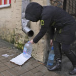 
              Kateryna Luchkina, a 31-year-old worker at Kyiv’s Department of Health, collects rainwater from a drainpipe in Kyiv, Ukraine, on Thursday. Nov. 24, 2022. Residents of Ukraine's bombed but not cowed capital roamed the streets with empty bottles in search of water and crowded into cafés for warmth, light and power Thursday, switching defiantly into survival mode after new Russian missile strikes the previous day plunged the city of 3 million and much of the country into the dark in winter.  (AP Photo/John Leicester)
            