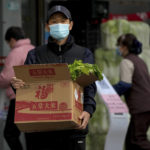 
              A man wearing a face mask carries a box with groceries as he leaves a supermarket in Beijing, Sunday, Nov. 27, 2022. Protests against China's strict zero-COVID policies in Shanghai continued on Saturday afternoon, after police cleared away hundreds of protesters in the early morning hours with force and pepper spray. (AP Photo/Andy Wong)
            