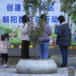 
              A child wearing a face mask plays herself as masked residents stand in line for their routine COVID-19 tests at a coronavirus testing site inside a residential compound in Beijing, Tuesday, Nov. 15, 2022. China's ruling party called for strict adherence to the hard-line "zero-COVID" policy Tuesday in an apparent attempt to guide public perceptions after regulations were eased slightly in places. (AP Photo/Andy Wong)
            