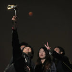
              Residents pose for a selfie as the moon rises during a lunar eclipse in Beijing, China, Tuesday, Nov. 8, 2022. (AP Photo/Ng Han Guan)
            