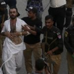 
              Police officers detain a supporter of former Pakistani Prime Minister Imran Khan's party, 'Pakistan Tehreek-e-Insaf' during a protest to condemn a shooting incident on their leader's convoy, in Karachi, Pakistan, Friday, Nov. 4, 2022. Khan who narrowly escaped an assassination attempt on his life the previous day when a gunman fired multiple shots and wounded him in the leg during a protest rally is listed in stable condition after undergoing surgery at a hospital, a senior leader from his party said Friday. (AP Photo/Fareed Khan)
            