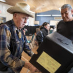 
              Paul Klopfer, left, is helped by election volunteer Isidor Abeita to introduce his ballot into the counting machine at a polling center in the South Valley area of Albuquerque, N.M., Tuesday, Nov. 8, 2022 (AP Photo/Andres Leighton)
            