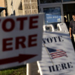 
              Signs point to the entrance on the last day of early voting before the midterm election as a man walks out of a polling site in Cranston, R.I., Monday, Nov. 7, 2022. (AP Photo/David Goldman)
            