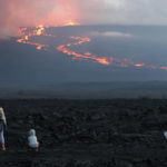 
              Spectators watch the lava flow down the mountain from the Mauna Loa eruption, Tuesday, Nov. 29, 2022, near Hilo, Hawaii. (AP Photo/Marco Garcia)
            