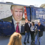 
              Pennsylvania Republican gubernatorial candidate Doug Mastriano and his wife Rebecca pause to speak with talk show host John Fredericks next to Fredericks' bus with an image of former President Donald Trump before the start of a campaign event at Crossing Vineyards and Winery in Newtown, Pa., Monday, Nov. 7, 2022. (AP Photo/Carolyn Kaster)
            