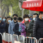 
              People wearing face masks stand in line for COVID-19 tests at a coronavirus testing site in Beijing, Thursday, Nov. 10, 2022. A surge in COVID-19 cases has spurred lockdowns in the southern Chinese manufacturing hub of Guangzhou, adding to financial pressure that has disrupted global supply chains and sharply slowed growth in the world's second-largest economy. (AP Photo/Mark Schiefelbein)
            