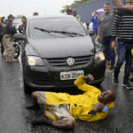 
              A supporter of President-elect Luiz Inacio Lula da Silva slips on a rain soaked pavement as he continues to chant slogans surrounded by truckers loyal to outgoing President Jair Bolsonaro blocking a highway, in Itaborai, Rio de Janerio state, Brazil, Tuesday, Nov. 1, 2022. Truckers supportive of Bolsonaro blocked hundreds of roads early Tuesday to protest his election loss to Lula da Silva. (AP Photo/Silvia Izquierdo)
            