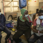 
              Migrants sit on the deck before being disembarked from the Norway-flagged Geo Barents rescue ship carrying 572 migrants, in Catania's port, Sicily, southern Italy, Sunday, Oct. 6, 2022. The Geo Barents, and the German-flagged Humanity1 have been allowed to disembark what the Italian authorities defined "vulnerable people" and minors, while other two ships carrying rescued migrants remained at sea. (AP Photo/Massimno Di Nonno)
            