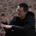 
              Fang Yuan, an engineer with Turenscape which helped design the "Fish Tail" sponge park that's built on a former coal ash dump site, holds up a permeable volcanic rock to show a plant sprouting from it in Nanchang in north-central China's Jiangxi province on Sunday, Oct. 30, 2022. Yuan said the park serves as “an ecological aquarium,” capable of retaining 1 million cubic meters of water during floods and can keep water in use, instead of just discharging it into the sewage system. (AP Photo/Ng Han Guan)
            