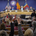 
              People wave their hands in protest during the Maricopa County Board of Supervisors during their general election canvass meeting, Monday, Nov. 28, 2022, in Phoenix. (AP Photo/Matt York)
            