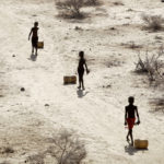 
              Young boys pull containers of water as they return to their huts from a well in the village of Ntabasi village in Samburu East, Kenya, Oct, 14, 2022. Loss and damage is the human side of a contentious issue that will likely dominate climate negotiations in Egypt. (AP Photo/Brian Inganga)
            