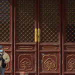 
              A man wearing a face mask walks past wooden screen doors at the Temple of Heaven in Beijing, Saturday, Nov. 12, 2022. Everyone in a district of 1.8 million people in China's southern metropolis of Guangzhou was ordered to stay home Saturday to undergo virus testing and a major city in the southwest closed schools as another rise in infections was reported. (AP Photo/Mark Schiefelbein)
            
