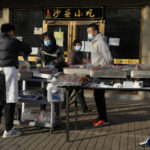 
              Residents buy cooked food from a vendor selling on the street after restaurants were order closed in Beijing, Friday, Nov. 25, 2022. Residents of China's capital were emptying supermarket shelves and overwhelming delivery apps Friday as the city government ordered accelerated construction of COVID-19 quarantine centers and field hospitals. (AP Photo/Ng Han Guan)
            