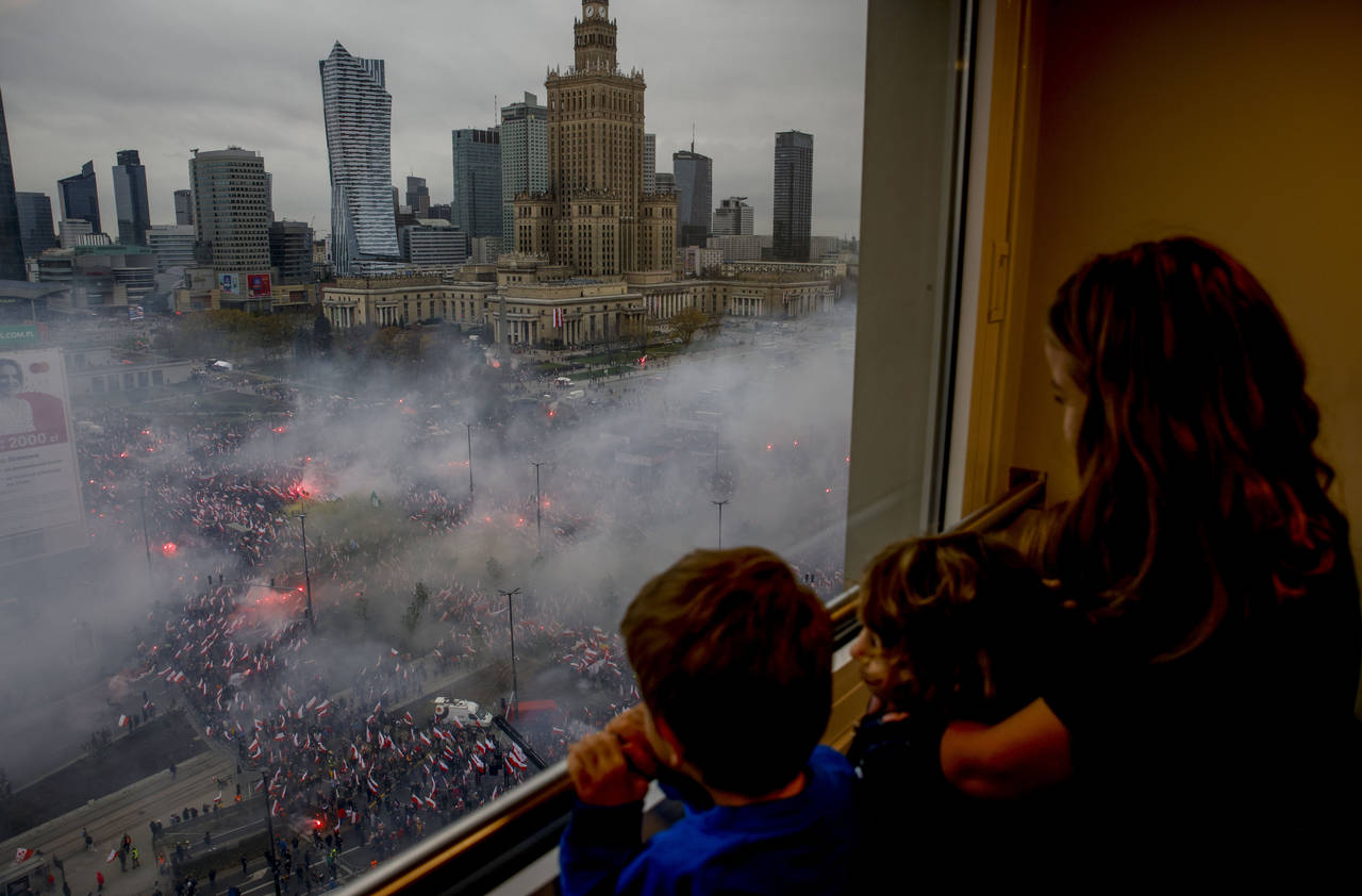 Children watch from a window as thousands of people have gathered in the city center for a yearly I...
