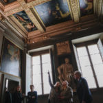 
              People look at the original site where the "Allegory of Inclination", top left, a 1616 work by Artemisia Gentileschi, now replaced by a photographic reproduction, before it was removed to undergo restoration, in the Casa Buonarroti Museum, in Florence, Italy, Wednesday, Nov. 9, 2022. Restorers have begun a six-month project on the "Allegory of Inclination" using modern techniques including x-rays and UV infrared research to go beneath the veils painted over the original to cover nudities and discover the work as Gentileschi painted it. (AP Photo/Andrew Medichini)
            