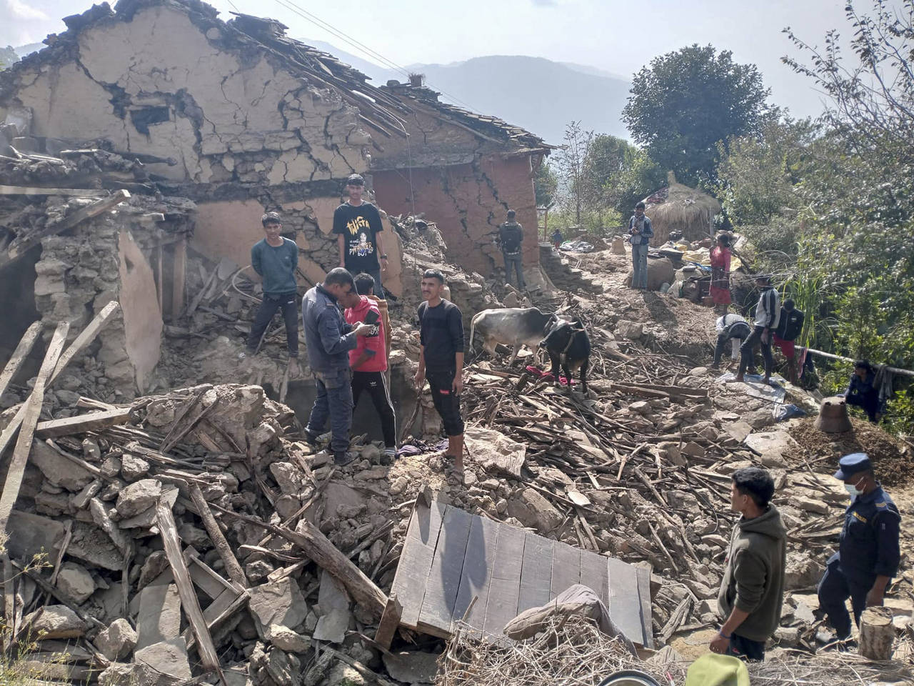 Nepalese villagers stand amidst the debris of their mudhouses after an earthquake in Doti district,...
