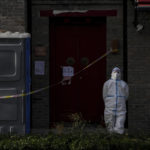 
              A worker in protective gear stands guard near caution tape placed in a locked down neighborhood in Beijing, Tuesday, Nov. 29, 2022. Chinese universities are sending students home as the ruling Communist Party tightens anti-virus controls and tries to prevent more protests after crowds angered by its severe "zero COVID" restrictions called for President Xi Jinping to resign in the biggest show of public dissent in decades. (AP Photo/Andy Wong)
            