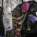 
              People collect water, in Kyiv, Ukraine, Thursday, Nov. 24, 2022. Residents of Ukraine's bombed but undaunted capital clutched empty bottles in search of water and crowded into cafés for power and warmth Thursday, switching defiantly into survival mode after new Russian missile strikes a day earlier plunged the city and much of the country into the dark.  (AP Photo/Evgeniy Maloletka)
            