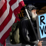 
              A man protests outside the Maricopa County Board of Supervisors auditorium prior to the board's general election canvass meeting, Monday, Nov. 28, 2022, in Phoenix. (AP Photo/Matt York)
            