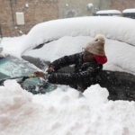 
              Zaria Black, 24, from Buffalo, clears off her car as snow falls Friday, Nov. 18, 2022, in Buffalo, N.Y.  A dangerous lake-effect snowstorm paralyzed parts of western and northern New York, with nearly 2 feet of snow already on the ground in some places and possibly much more on the way.  (AP Photo/Joshua Bessex)
            