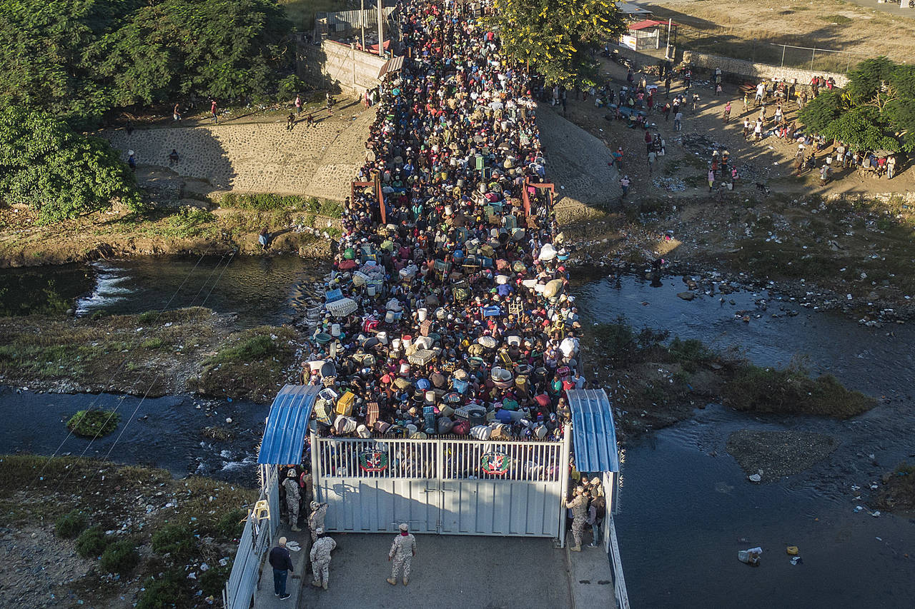 FILE - Haitians wait to cross the border between Dominican Republic and Haiti in Dajabon, Dominican...