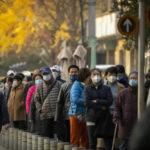 
              People wearing face masks wait for COVID-19 tests at a coronavirus testing site in Beijing, Thursday, Nov. 17, 2022. Chinese authorities faced more public anger Thursday after a second child's death was blamed on overzealous anti-virus enforcement, adding to frustration at controls that are confining millions of people to their homes and sparked fights with health workers. (AP Photo/Mark Schiefelbein)
            