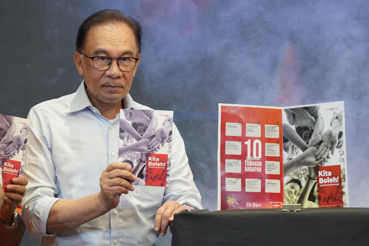 Malaysian opposition leader Anwar Ibrahim shows a copy of manifesto of his Pakatan Harapan (The All...