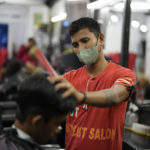 
              Jeremy Garing cuts the hair of a customer at a salon in Tacloban, Leyte province, central Philippines on Tuesday, Oct. 25, 2022. Garing works as a barber to feed his family, now living in a new community for victims of super Typhoon Haiyan after their village was wiped out when it struck on 2013, killing six family members and his daughter. (AP Photo/Aaron Favila)
            