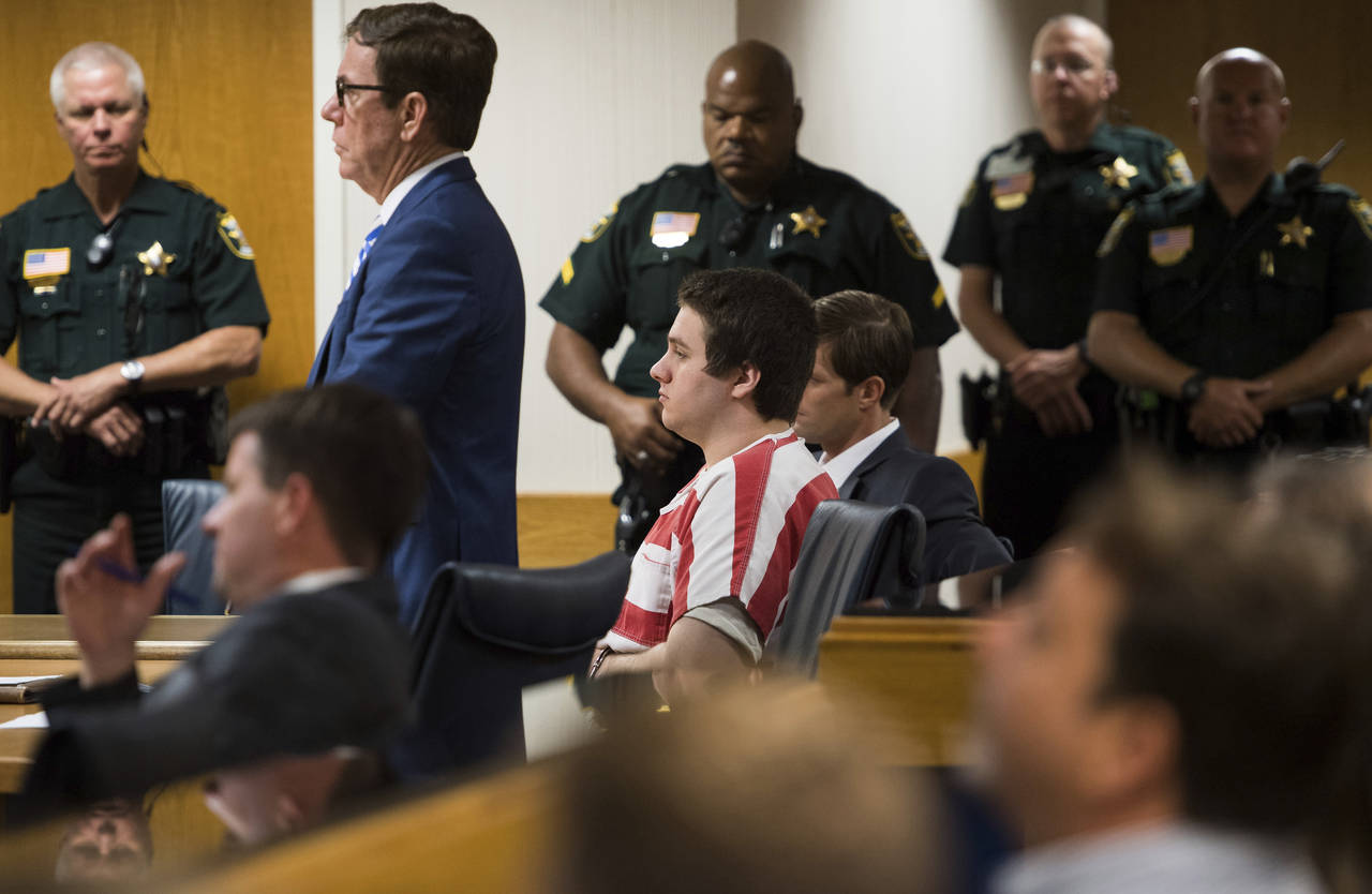 FILE - Austin Harrouff, center, wearing stripes, accused of brutally killing a Tequesta couple in 2...