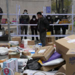 
              Residents wait for their deliveries behind shelves outside a community in Beijing, Thursday, Nov. 24, 2022. China is expanding lockdowns, including in a central city where factory workers clashed this week with police, as its number of COVID-19 cases hit a daily record. (AP Photo/Ng Han Guan)
            