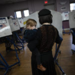 
              A member of the Orthodox Jewish community carries her child as she fills out ballot papers at a polling center on, Tuesday, Nov. 8, 2022, in the Brooklyn borough of New York. (AP Photo/Wong Maye-E)
            