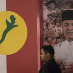 
              A man stand in front picture of UMNO president Ahmad Zahid Hamidi at party headquarters in Kuala Lumpur, Malaysia, Sunday, Nov. 20, 2022. Zahid, who is fighting dozens of graft charges, faces pressure to resign after UMNO's second drubbing at the polls. (AP Photo/Ahmad Yusni)
            
